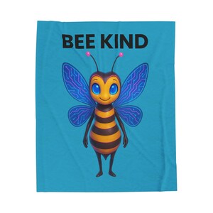 May include: A turquoise blanket with a cartoon bee illustration. The bee has blue and purple wings, a yellow and black striped body, and the words "BEE KIND" in black.
