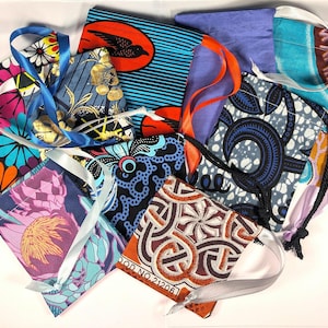 May include: A collection of colorful fabric drawstring bags with various patterns, including floral, geometric, and abstract designs. The bags are made of cotton and have a variety of colors, including blue, orange, green, and brown.