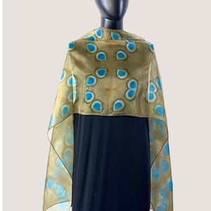 May include: A sheer scarf with a light brown background and blue and green abstract pattern.