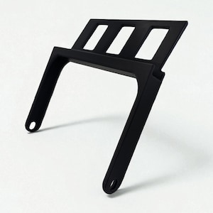 May include: A black metal stand with a rectangular top featuring three rectangular cutouts. The stand has two angled legs with circular holes at the bottom. The object is set against a white background.