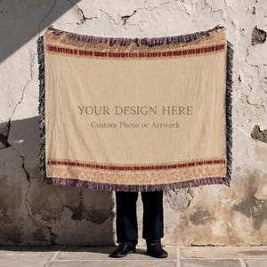 Könnte beinhalten: Eine rechteckige Webdecke mit beigefarbener Mitte, auf der der Text "YOUR DESIGN HERE" und "Custom Photo or Artwork" in dunkler Schrift steht, umrahmt von dekorativen kastanienbraunen und beigen Musterrändern mit Fransen an allen Seiten.