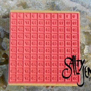 May include: Red rubber stamp with a grid of numbers from 0 to 99. The stamp is mounted on a wooden base. The text "SALLY JEN Studio" is printed in black on the right side of the stamp.