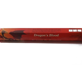 Może przedstawiać: Czerwone pudełko z kadzidłem Dragon's Blood z ilustracją smoka i tekstem "Dragon's Blood Magical Powers Le Song De Dragons".