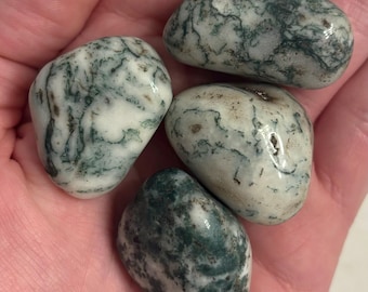 May include: Four tumbled moss agate stones with green and white swirling patterns. The stones are smooth and polished.