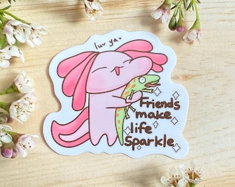 Puede incluir: Un ajolote rosa con un lagarto verde en sus brazos. El ajolote está sonriendo y el lagarto está sacando la lengua. El texto "luv ya" está por encima del ajolote y el texto "Friends make life sparkle" está por debajo del ajolote.