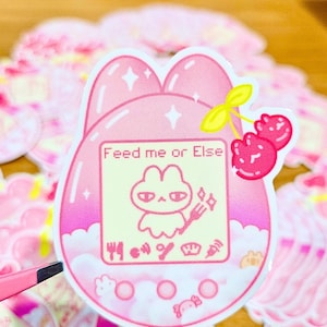 Adesivo "Dai da mangiare o altrimenti" - Adesivo Tamagotchi coniglietto rosa estetico / 2,5" impermeabile / Design carino di capibara, axolotl e coniglietto