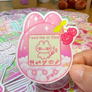Grado B - Adesivo "Dammi da mangiare o altro" - Adesivo Tamagotchi coniglietto rosa estetico / 2,5" impermeabile / Design carino con capibara, axolotl e coniglietto