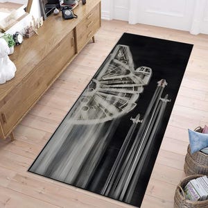 Puede incluir: Alfombra de área negra y blanca con un gráfico del Millennium Falcon y tres cazas X-wing volando en formación.