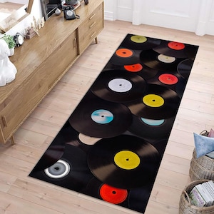 May include: A black and white vinyl record rug with a variety of colored vinyl records arranged in a circular pattern. The rug is perfect for adding a touch of vintage style to any room.
