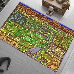 Könnte beinhalten: Ein rechteckiger Teppich mit einem detaillierten Pixel-Art-Kartendesign in der Draufsicht. Die Grafik zeigt eine lebendige Landschaft mit grünen Wäldern, braunen Gebirgszügen, blauen Gewässern und verschiedenen kleinen Strukturen in einem Raster.