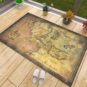 May include: A rectangular area rug featuring a detailed, vintage-style map of Middle-earth with a tan and brown color palette. The map includes geographical labels, a compass rose, and the text Middle-earth in a decorative frame at the top left.
