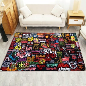 Könnte beinhalten: Ein schwarzer Teppich mit einer Collage aus bunten Bandlogos und -namen, darunter Nirvana, KISS, Ramones und Slayer. Der Teppich ist eine Mischung aus Schwarz, Rot, Gelb, Weiß und Blau.