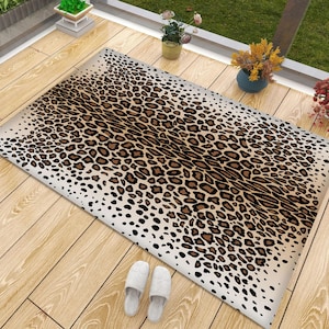 Puede incluir: Una alfombra de área marrón y beige con un patrón de estampado de leopardo. La alfombra tiene un efecto degradado, con el estampado de leopardo volviéndose más denso hacia el centro.