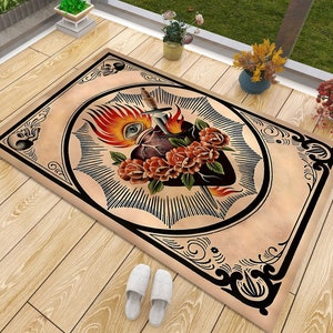 Puede incluir: Una alfombra beige con un borde negro y un diseño detallado de un corazón atravesado por una daga, rodeado de llamas y rosas.
