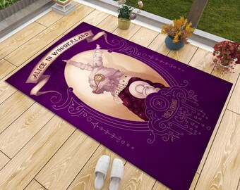 May include: A rectangular purple area rug featuring a central illustration of a white rabbit wearing a monocle and vest. The text ALICE IN WONDERLAND appears on a banner at the top, with BY LEWIS CARROLL printed in a circular frame at the bottom.