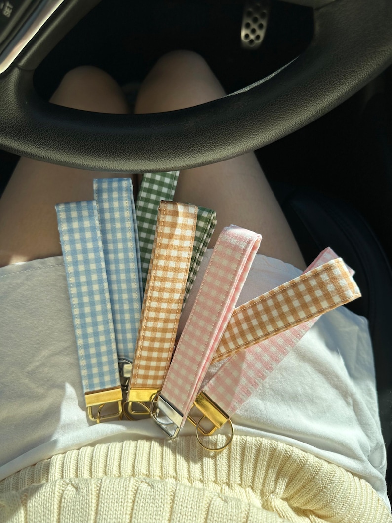 May include: Six different colored gingham keychains with gold key rings. The keychains are light blue, brown, pink, green, and two shades of pink.