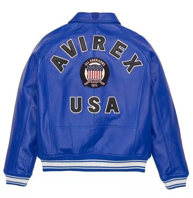 May include: A vibrant blue leather jacket with the word "AVIREX" arched across the back in white block letters. Below the name is a circular patch with the words "ALL AMERICANS ESTABLISHED 1975" and a USA flag design. The word "USA" is printed below the patch.