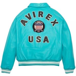 May include: A turquoise leather jacket with the word "AVIREX" arched across the shoulders and "USA" below. A circular patch with the American flag and the words "ALL AMERICANS ESTABLISHED 1975" is centered. The jacket has a white and blue striped trim.