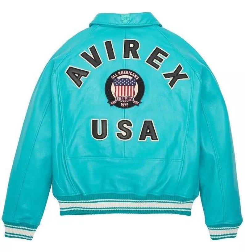 May include: A turquoise leather jacket with the word "AVIREX" arched across the shoulders and "USA" below. A circular patch with the American flag and the words "ALL AMERICANS ESTABLISHED 1975" is centered. The jacket has a white and blue striped trim.