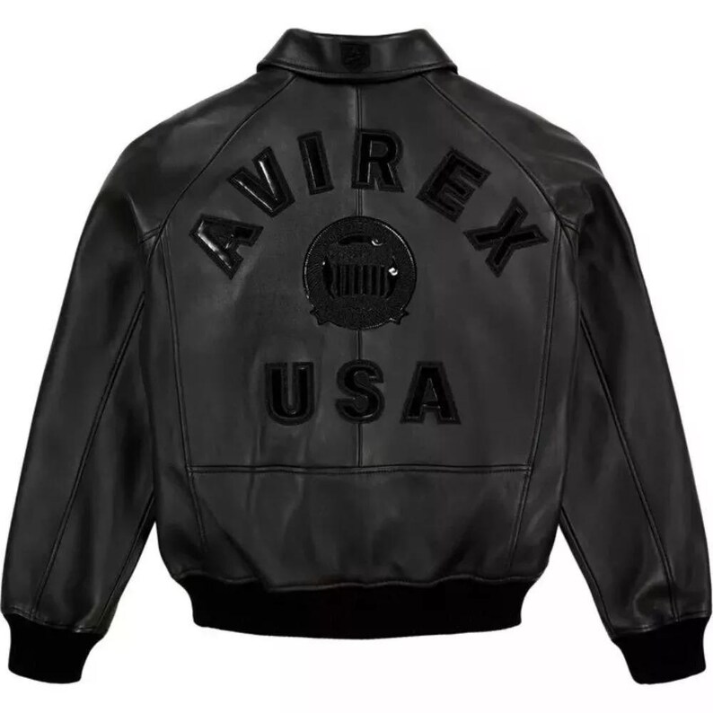 May include: Black leather jacket with the word "AVIREX" arched across the shoulders and "USA" below a circular emblem. The jacket has a ribbed hem and cuffs, and a classic collar.