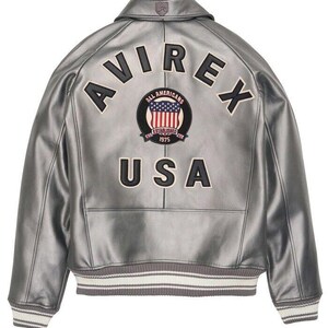 May include: Silver leather jacket with the word "AVIREX" across the back, above a circular patch with the American flag and the words "ALL AMERICANS ESTABLISHED 1975 USA". The jacket has a ribbed collar and cuffs.