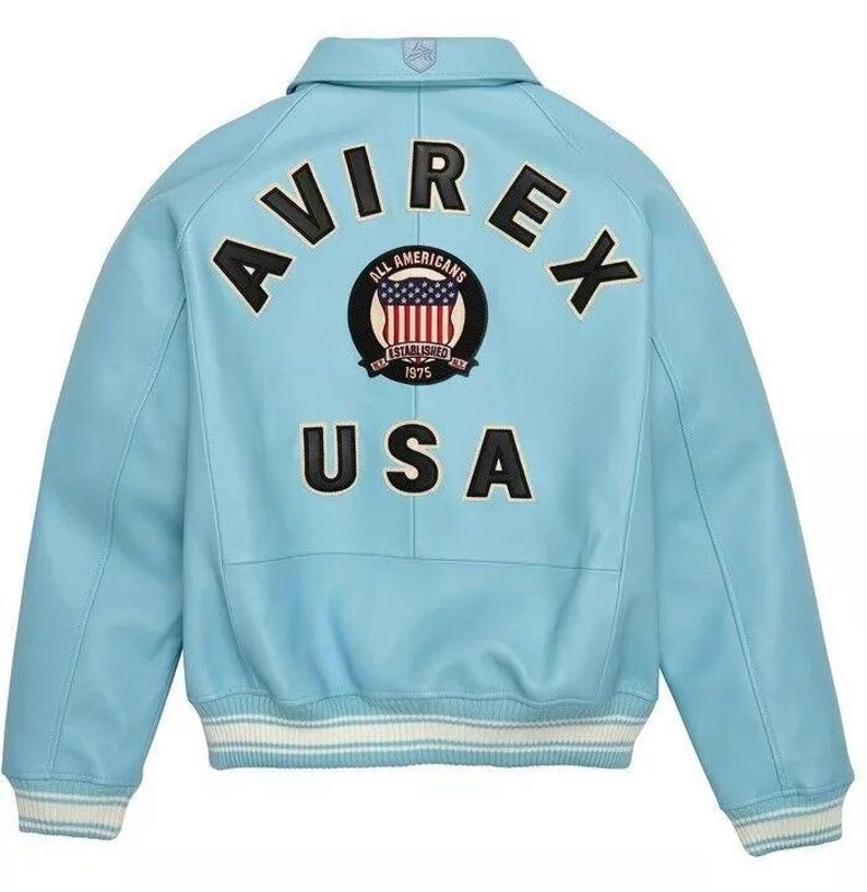 May include: A light blue leather jacket with the word "AVIREX" across the back in black block letters. Below the word "AVIREX" is a circular patch with the words "ALL AMERICANS ESTABLISHED 1975" and a graphic of the American flag. The word "USA" is below the patch.