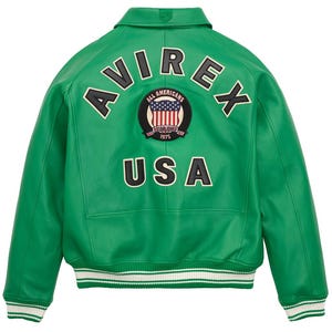 May include: A vibrant green leather jacket with the word "AVIREX" arched across the upper back. Below the text is a circular patch with the American flag and the words "ALL AMERICANS ESTABLISHED 1975". The word "USA" is below the patch. The jacket has a white and green striped hem.