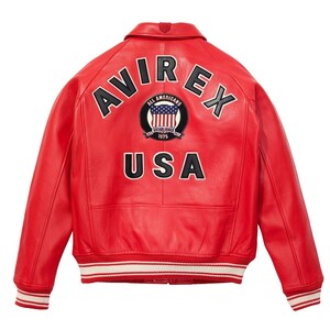 May include: A red leather jacket with the word "AVIREX" arched across the shoulders in white lettering. Below the word "AVIREX" is a circular patch with the words "ALL AMERICANS" and a US flag design. The word "USA" is displayed in white block letters.