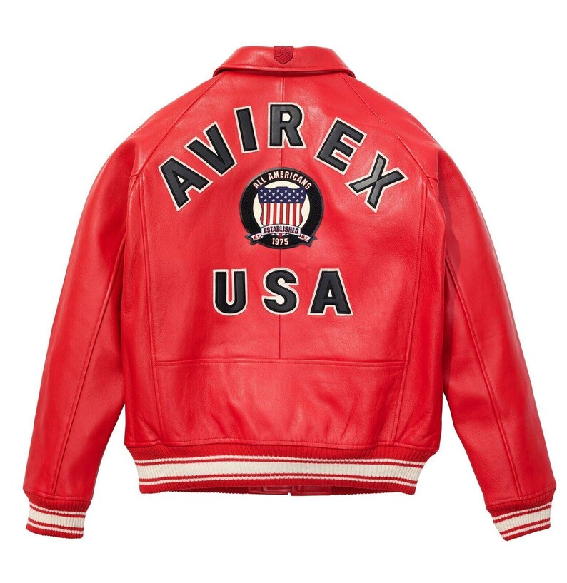 May include: A red leather jacket with the word "AVIREX" arched across the shoulders in white lettering. Below the word "AVIREX" is a circular patch with the words "ALL AMERICANS" and a US flag design. The word "USA" is displayed in white block letters.