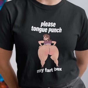 Könnte beinhalten: Schwarzes T-Shirt mit dem Text "please tongue punch my fart box" und einer Cartoon-Illustration des Gesäßes einer Person. Das T-Shirt wird von einer Person mit blonden Haaren getragen.