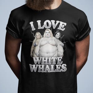 Op de afbeelding: Zwart t-shirt met de witte tekst "I LOVE WHITE WHALES" boven een illustratie van drie vrouwen. De persoon die het t-shirt draagt, is een man met een volle baard en een zonnebril.