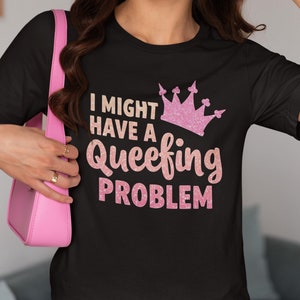 May include: Black t-shirt with a pink glitter crown and the text "I might have a queefing problem".