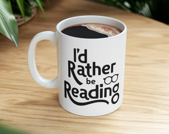 May include: White ceramic coffee mug with a black handle and the text "I'd Rather Be Reading" with a pair of glasses icon.