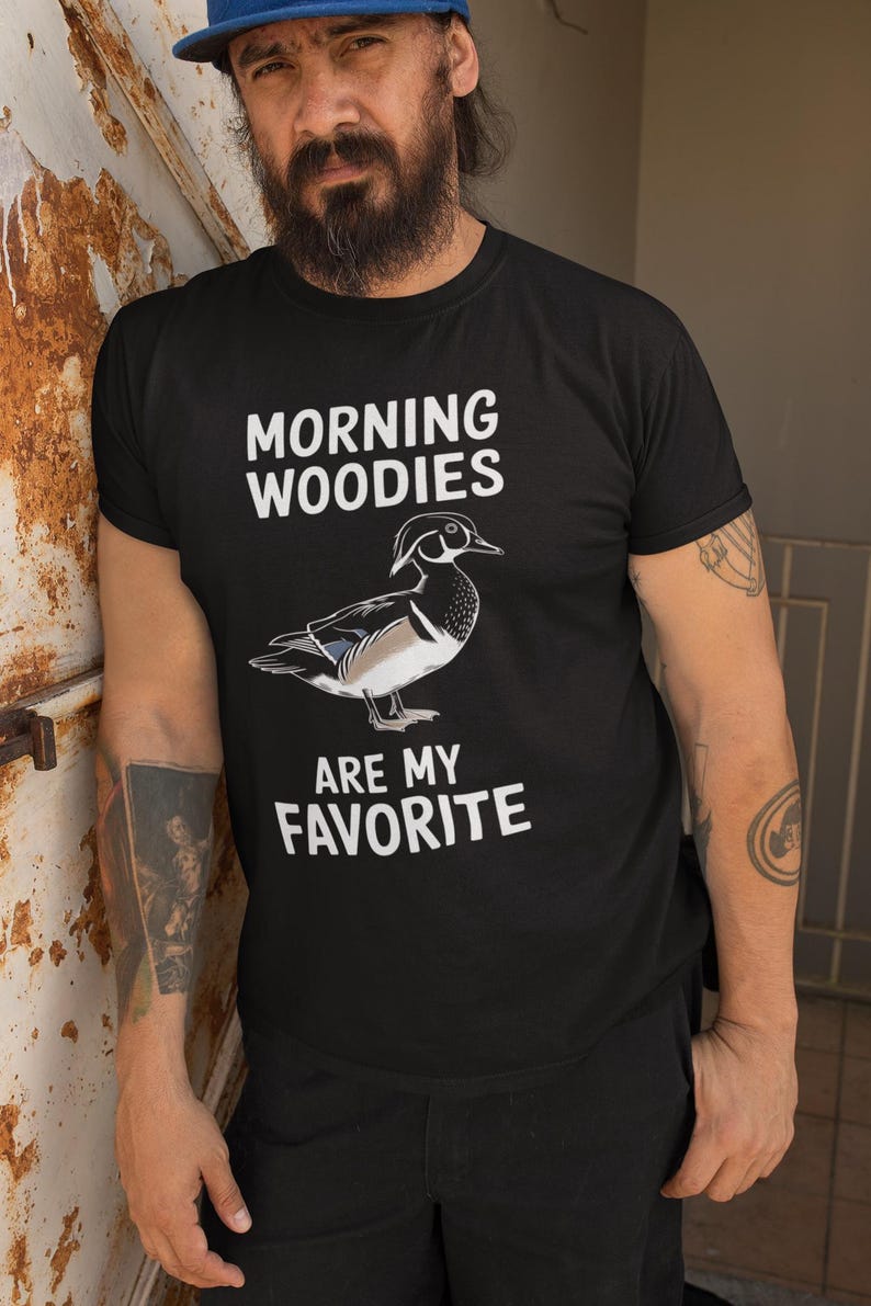 May include: A black t-shirt with white text that reads "Morning Woodies are my favorite". A cartoon wood duck is pictured above the text.