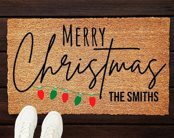 May include: A brown doormat with the text "Merry Christmas The Smiths" in black lettering. The text is decorated with a string of red and green Christmas lights.
