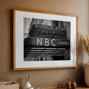 May include: Black and white photograph of the Rainbow Room, an observation deck in New York City. The sign reads "Rainbow Room Observation Deck NBC Studios".