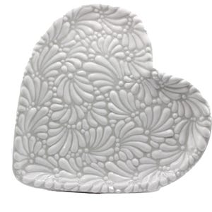 May include: A white, heart-shaped ceramic dish with a raised floral pattern. The dish has a slightly curved edge and a matte finish. The design features a repeating pattern of stylized flowers.