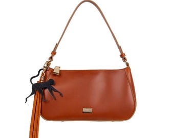 May include: A brown leather handbag with a gold zip and a black monkey keychain with a brown tassel.