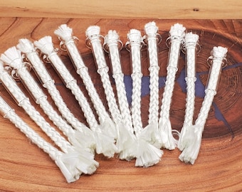 May include: A group of 18 white braided wicks with glass tubes. The wicks are arranged in a fan shape on a wooden surface.