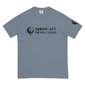 May include: A light blue t-shirt featuring a black logo that reads "Mooncast Productions" with a sword inside a circle.