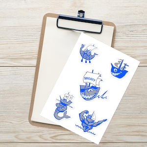 May include: A sheet of stickers featuring blue and grey illustrations of boats, mermaids, and a shark. The stickers have a cartoon style and include the text "SBOATY".