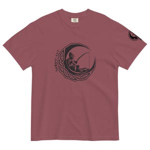 May include: A maroon t-shirt featuring a black graphic of a person fishing from a crescent moon with the word "MOONCAST" written vertically on the left side of the moon.