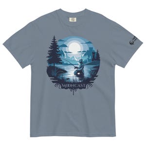 May include: A blue t-shirt featuring a graphic of a knight fishing in a lake under a full moon. The graphic is enclosed in a circle with the text "MOONCAST" at the bottom.