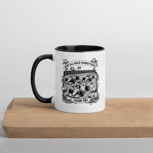 May include: White ceramic coffee mug with a black rim and handle. The mug features a black and white illustration of race cars on a track with the text "May all race conditions favor you".