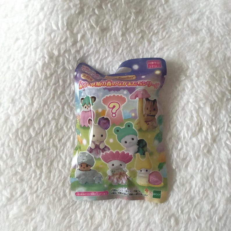May include: Sealed package of miniature animal figurines. The package features various colorful figures, including a bear, rabbit, and frog, all wearing whimsical outfits. The package has Japanese text and a question mark graphic.