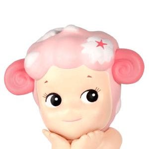 Pu&ograve; includere: Statuetta rosa chiaro di un personaggio seduto con la testa a forma di pecora. La testa ha un design rosa a forma di nuvola con una stella rossa. Il personaggio ha grandi occhi neri e si tiene le mani vicino al viso.