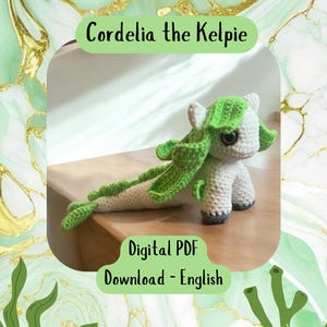 May include: A crocheted amigurumi kelpie named Cordelia, with a white body, green mane and tail, and large black eyes. The amigurumi is sitting on a wooden surface. The image text reads "Cordelia the Kelpie" and "Digital PDF Download - English".