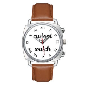May include: A wristwatch with a silver square case, a white dial featuring black Roman numerals, and the text "custom watch" in black script. The watch has silver hour, minute, and red second hands, and a smooth brown leather strap.