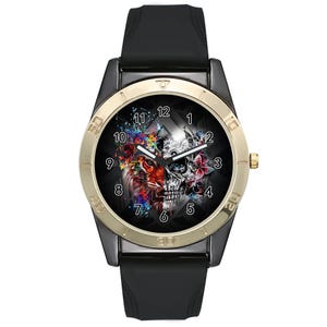 May include: A wristwatch with a black silicone strap and a dark case featuring a gold-toned bezel. The watch face displays a split graphic design with a colorful lion on the left and a monochrome skull on the right, surrounded by white numerals.