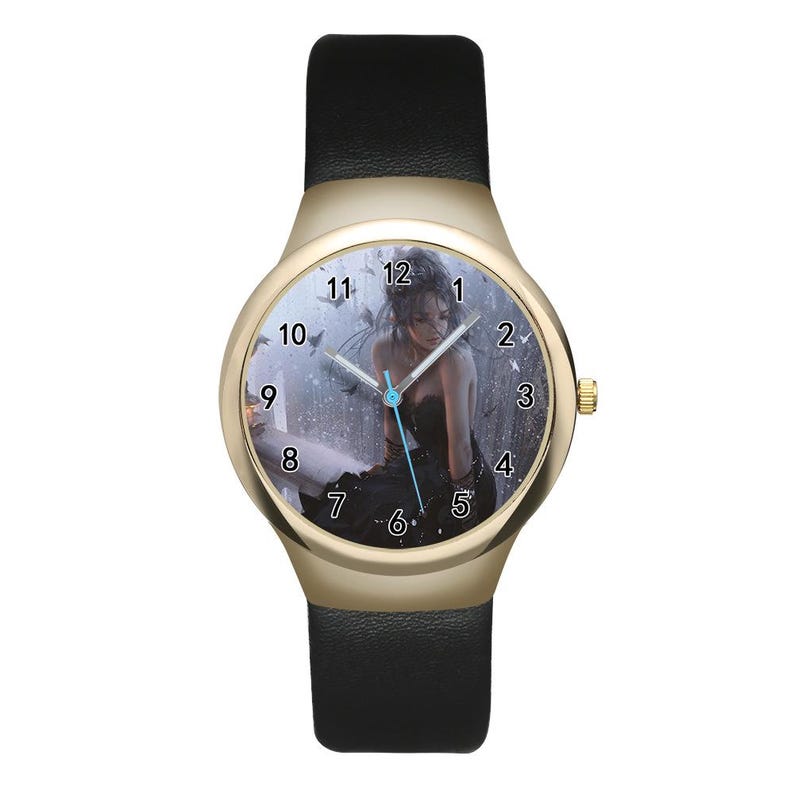 May include: A wristwatch with a gold-tone round case and a black leather strap. The watch face features a graphic illustration of a person in a black dress sitting in a rainy setting, with black Arabic numerals and silver hour, minute, and second hands.